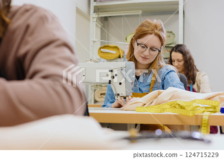 Three women seamstresses and fashion designers work in for sewing machines, clothing production. 124715229