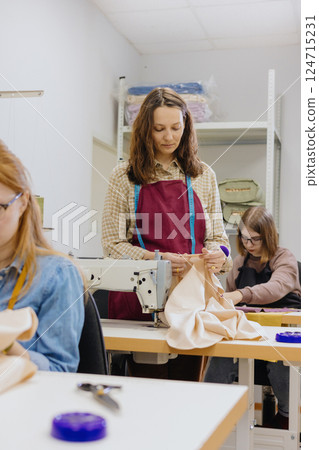 Three women seamstresses and fashion designers work in for sewing machines, clothing production. 124715231