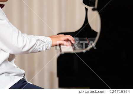 Hands of a boy playing the piano 124716554