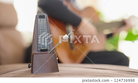 Metronome ticking while musician plays acoustic guitar Metronome ticking while musician plays acoustic guitar 124716998