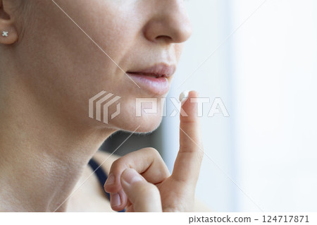 Woman applying cream on dry lips. Closeup, selective focus. 124717871