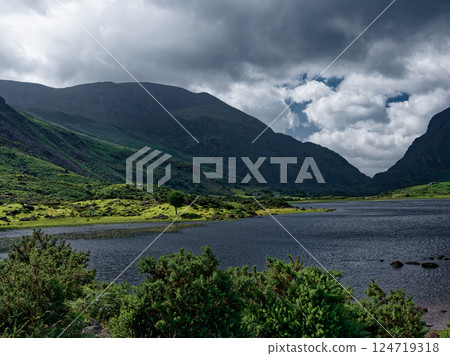 Nestled between rolling hills and valleys, Black Lake offers a tranquil setting in Ireland, with cloudy skies, water's surface, creating a serene landscape. Nestled between rolling hills and valleys, Black Lake offers a tranquil setting in Ireland, with cloudy skies, water's surface, creating a serene landscape. 124719318