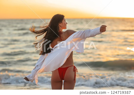Silhouette of the beautiful girl enjoying beautiful sunset on the beach Silhouette of the beautiful girl enjoying beautiful sunset on the beach 124719387