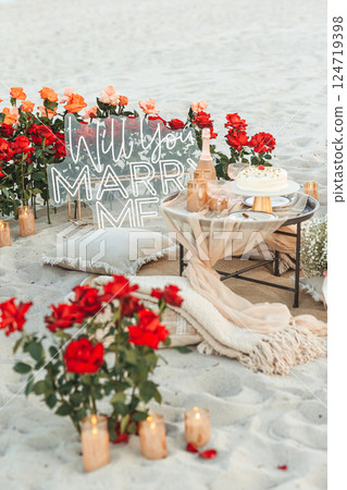 Beach Proposal Decor with Will You Marry Me Sign, Flowers and Cozy Area. Will You Marry Me Proposal Beach Proposal Decor with Will You Marry Me Sign, Flowers and Cozy Area. Will You Marry Me Proposal 124719398