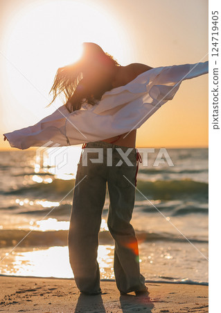 Silhouette of the beautiful girl enjoying beautiful sunset on the beach Silhouette of the beautiful girl enjoying beautiful sunset on the beach 124719405