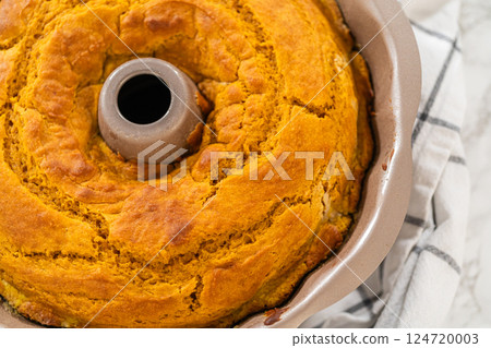 Cooling freshly baked pumpkin bundt cake on the kitchen counter. 124720003