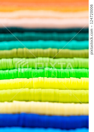 A vibrant collection of clay beads, neatly arranged by color on a white table, ready to inspire young crafters to create their own unique bracelets. A vibrant collection of clay beads, neatly arranged by color on a white table, ready to inspire young crafters to create their own unique bracelets. 124720006