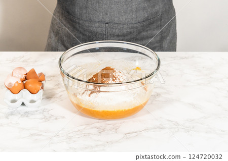 In a cozy kitchen, a large mixing bowl becomes the stage for expertly blending the ingredients, setting the scene for crafting a delightful homemade pumpkin bundt cake from cake mix. 124720032