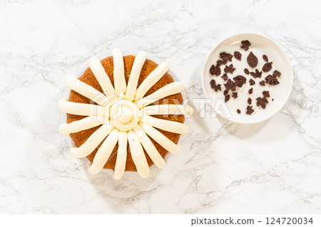 Flat lay. Icing the pumpkin bundt cake with cream cheese frosting and decorating it with chocolate leaves. 124720034