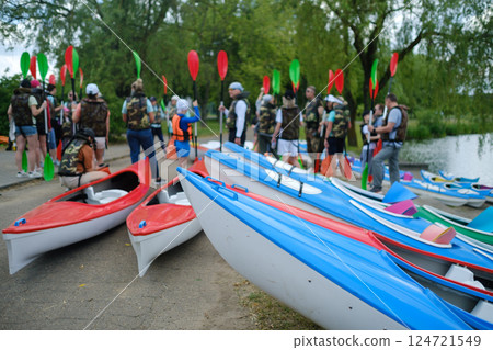 Kayaking event gathers enthusiasts by the riverside with colorful kayaks and paddles in a vibrant outdoor setting 124721549