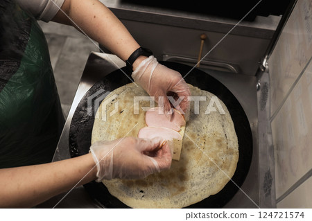 Preparing a delicious crepe with thinly sliced ham in a bustling kitchen during afternoon hours 124721574