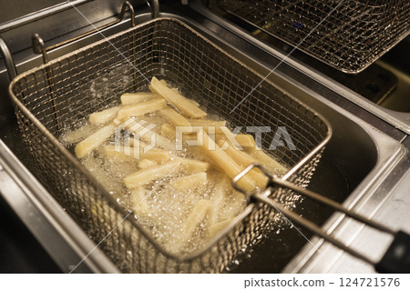 Crispy french fries being fried in a commercial kitchen during a busy lunchtime at a popular eatery Crispy french fries being fried in a commercial kitchen during a busy lunchtime at a popular eatery 124721576
