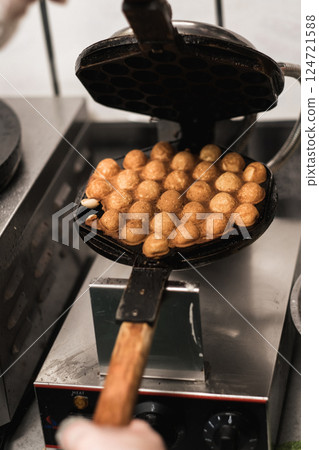 Delicious dessert being prepared in a kitchen with a traditional waffle maker during a busy afternoon Delicious dessert being prepared in a kitchen with a traditional waffle maker during a busy afternoon 124721588