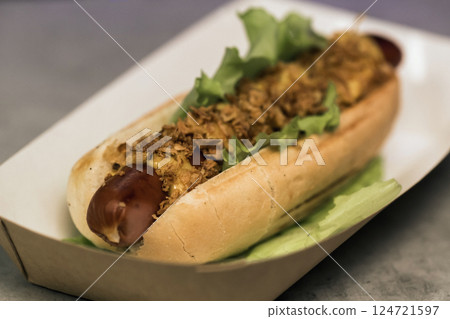 Delicious gourmet hot dog with toppings nestled in a biodegradable tray, ready to be enjoyed at a summertime outdoor food festival in the park Delicious gourmet hot dog with toppings nestled in a biodegradable tray, ready to be enjoyed at a summertime outdoor food festival in the park 124721597