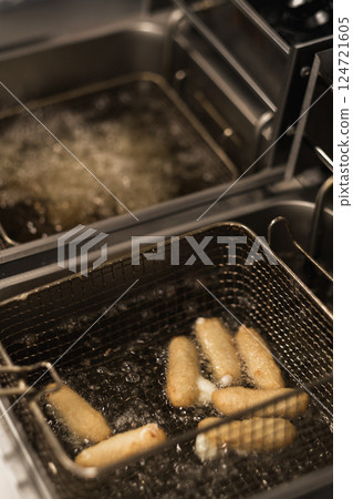 Hot oil frying spring rolls in a commercial kitchen at lunchtime, chefs busy preparing food for customers in a bustling restaurant Hot oil frying spring rolls in a commercial kitchen at lunchtime, chefs busy preparing food for customers in a bustling restaurant 124721605