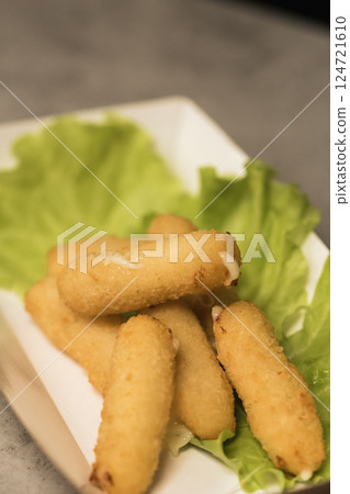 Crispy fried snacks arranged on lettuce leaves at a lively dining spot in the evening Crispy fried snacks arranged on lettuce leaves at a lively dining spot in the evening 124721610