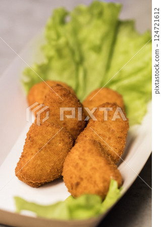 Crispy fried appetizers arranged beautifully on a bed of fresh lettuce in a casual dining setting during a sunny afternoon Crispy fried appetizers arranged beautifully on a bed of fresh lettuce in a casual dining setting during a sunny afternoon 124721612