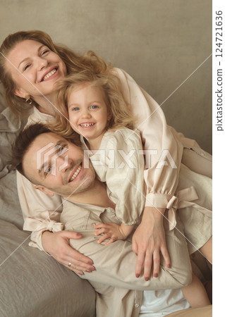 Family poses happily together in a cozy indoor setting, showcasing love and warmth 124721636