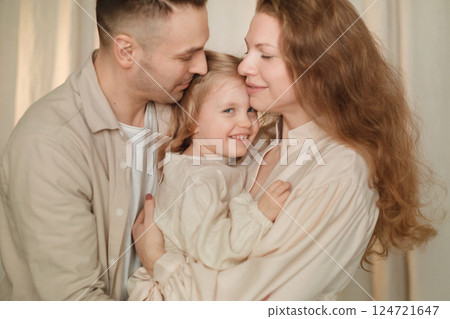 Family joy captured in a cozy indoor setting with parents embracing their playful child during a warm afternoon Family joy captured in a cozy indoor setting with parents embracing their playful child during a warm afternoon 124721647