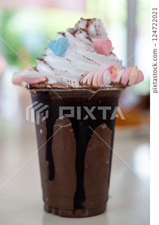 A cup of iced chocolate with whipped cream and marshmallow on the table A cup of iced chocolate with whipped cream and marshmallow on the table 124722021
