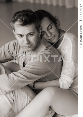Couple engaging in mindfulness meditation practice while seated back to back in a serene indoor space during the late afternoon light 124722047