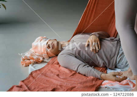 Relaxation and healing during a restorative yoga session with supportive props in a serene indoor environment 124722086