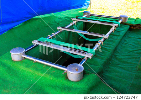 Silver holder for coffin is placed above freshly dug grave with silent surroundings during burial ceremony. 124722747