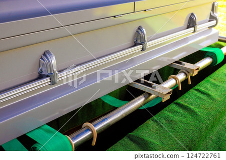 Funeral casket is prominently placed on green velvet surface, ready for burial ceremony in cemetery setting. Funeral casket is prominently placed on green velvet surface, ready for burial ceremony in cemetery setting. 124722761