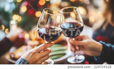 People clinking glasses of red wine celebrating christmas dinner party 124724128