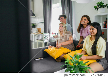 Friends playing video games together at home, leisure and entertainment concept Friends playing video games together at home, leisure and entertainment concept 124726042