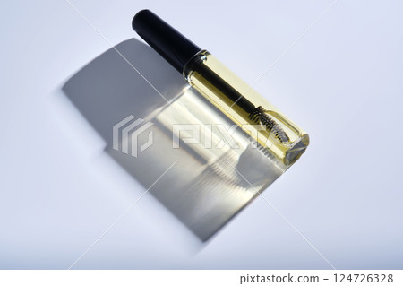 Bottle with brush filled with oil for eyebrow and eyelash growth.  124726328
