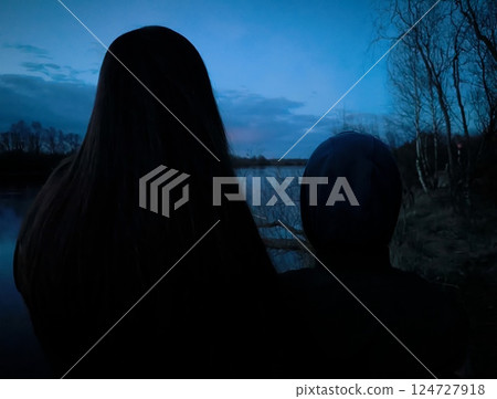 Mystical sunset over the river. Silhouette of woman and child against the background of a bright sunset. Nature background. purple sunset over the lake Mystical sunset over the river. Silhouette of woman and child against the background of a bright sunset. Nature background. purple sunset over the lake 124727918