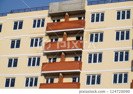 wall of a high-rise brick house, red balconies and yellow walls. 124728090