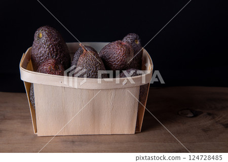 Hass avocados in wooden box. The Hass avocado is a variety of avocado with dark green bumpy skin. 124728485