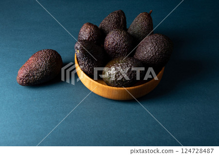 Hass avocados in wooden bowl on blue table. Hass avocados in wooden bowl on blue table. 124728487