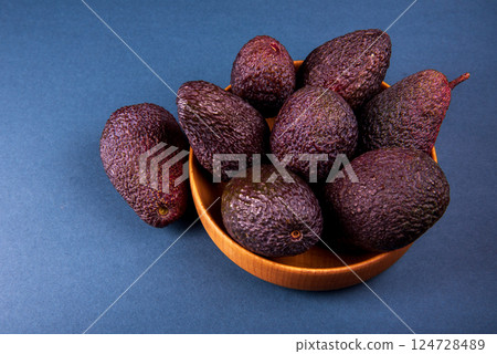 Hass avocados in wooden bowl on blue table Hass avocados in wooden bowl on blue table 124728489