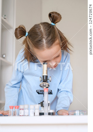 The child examines the particles under a microscope. Science in preschool education The child examines the particles under a microscope. Science in preschool education 124728674