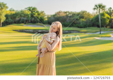 Mother and newborn baby on a meadow in the park. Tender bonding moment in nature. Parenthood, love, and family connection concept Mother and newborn baby on a meadow in the park. Tender bonding moment in nature. Parenthood, love, and family connection concept 124728703