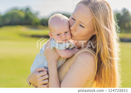 Mother and newborn baby on a meadow in the park. Tender bonding moment in nature. Parenthood, love, and family connection concept Mother and newborn baby on a meadow in the park. Tender bonding moment in nature. Parenthood, love, and family connection concept 124728831