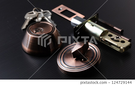 Small parts of Deadbolt lock to protect security safety on door window house. Incomplete many parts of deadbolt lock before assemble to door window with key over black background 124729144