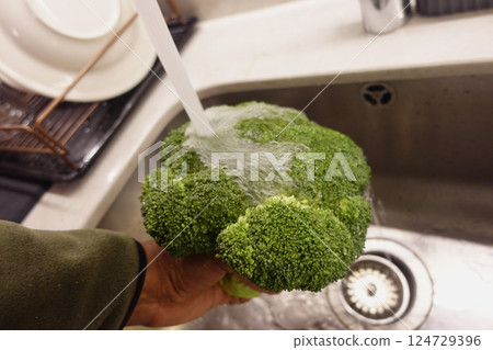 Fresh Broccoli is Being Thoroughly Rinsed in the Kitchen Sink for Preparation and Cleaning 124729396