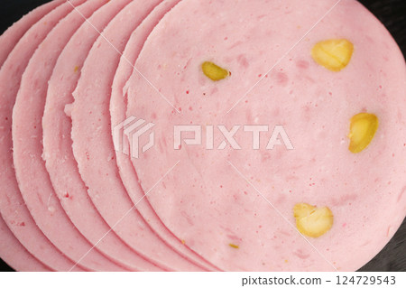 Slices of Pink Bologna paired with Pickles displayed on a Black Background for visual appeal 124729543