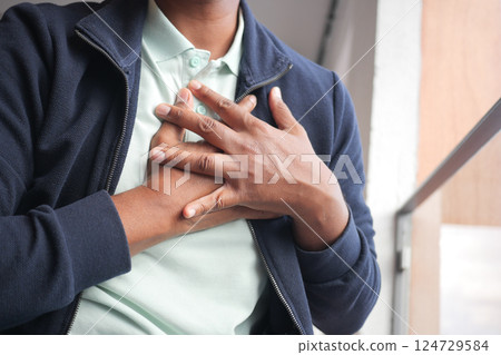young man suffering pain in heart and holding chest with hand  124729584