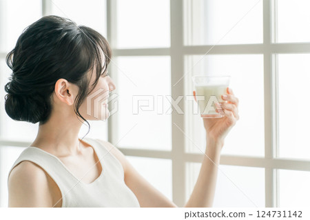 Asian woman drinking milk in the morning at home Asian woman drinking milk in the morning at home 124731142