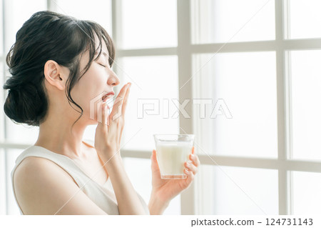 Sleepy Asian woman yawning drinking milk Sleepy Asian woman yawning drinking milk 124731143