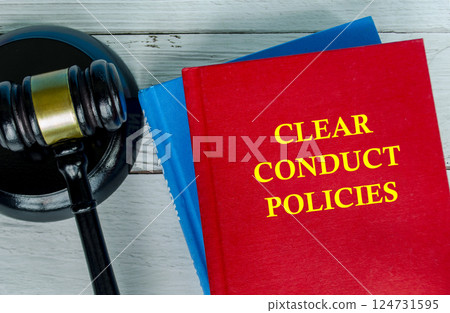 Top view of Clear Conduct Policies text on red cover book with gavel background. Work policies and procedures 124731595