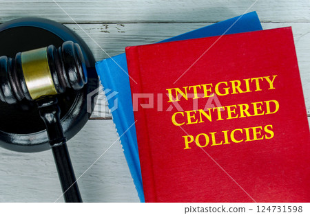 Top view of Integrity Centered policies text on red cover book with gavel background 124731598