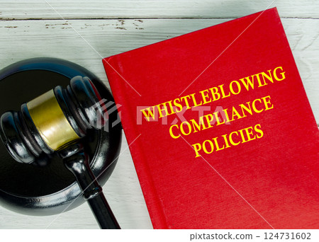 Top view of Whistleblowing Compliance Policies book with gavel background 124731602