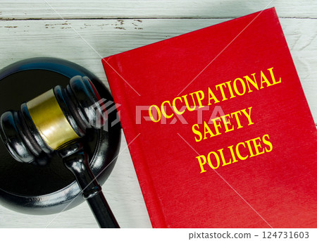 Top view of Occupational Safety policies text on red cover book with gavel background 124731603