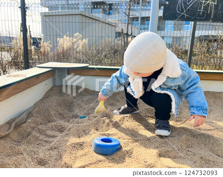 A small two-year-old child plays in the sandbox on the playground 124732093